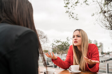 Two angry friends discussing while sitting at coffee shop.