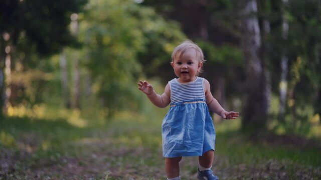 one year old baby learned to walk. little girl runs in the park alone