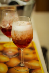 Hand pouring red alcoholic drink in glass with ice