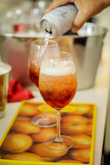 Hand pouring red alcoholic drink in glass with ice