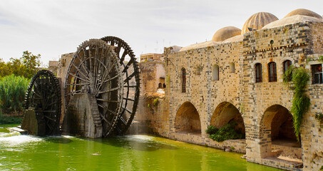 Noria of Hama, water wheel along the Orontes River in the city of Hama, Syria. - obrazy, fototapety, plakaty