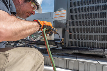 HVAC technician soldering copper line to condensing unit