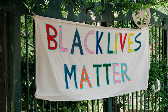 Black Lives Matter canvas banner handmade in a varity of colors hanging over a park entrance gate.
