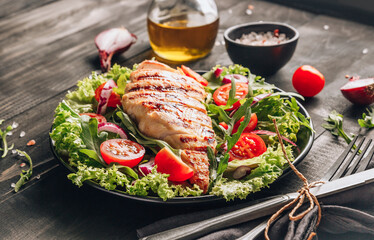 Grilled chicken fillet and fresh vegetable salad of tomatoes and arugula leaves. Healthy food. Black background.
