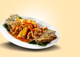 Fried mango sauce fish. Deep fried fish, smothered in sweet and sour sauce and sliced mango and chili, served on a plate covered with banana leaves.