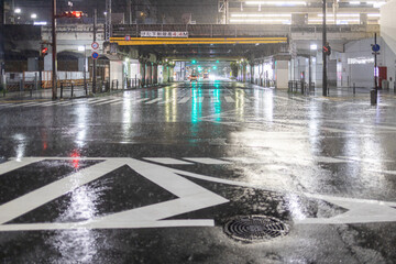Heavy rain on empty roadway in Japanese city at night