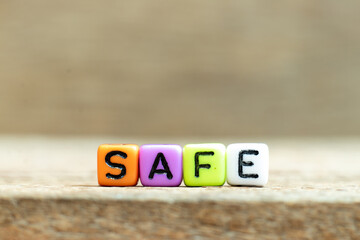 Colorful bead with black letter in word safe on wood background