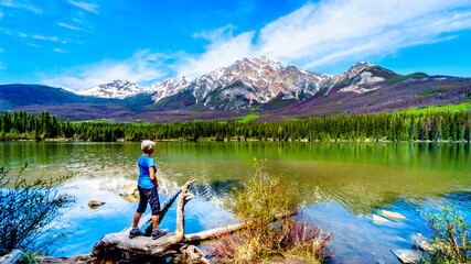 Senior woman looking at Pyramid Mountain in Pyramid Lake in Jasper National Park in Alberta, Canada. The mountains is part of the Victoria Cross Range in the Rocky Mountains
