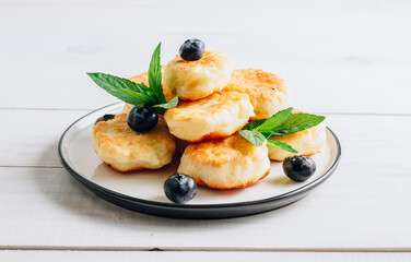 Trandy food - fluffy mini pancakes with blueberries and mint on a white wooden background.