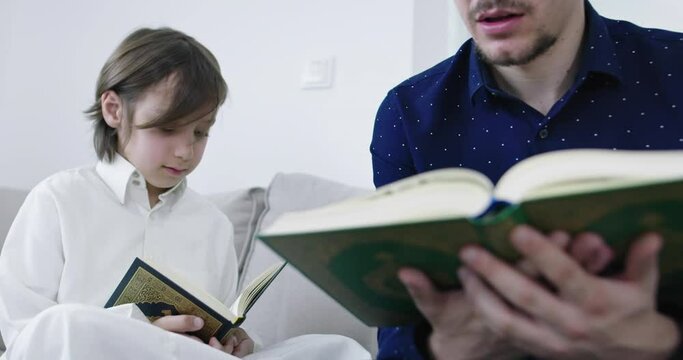Muslim father and son reading from the quran