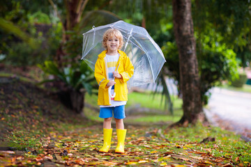 Obraz premium Child playing in autumn rain. Kid with umbrella.