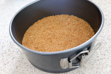 A graham cracker crust pressed into a silver metal spring form pan.