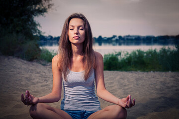 Blond haired lady is meditating in the park, seeking harmony and calmness