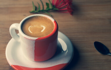Freshly brewed sparkling coffee in a small orange and white mug. Cup with typical Brazilian drink on a wooden board. Copy space.
