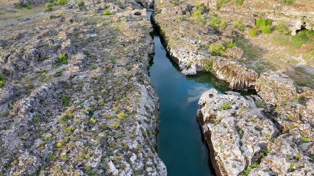 Narrow mountain river flowing through rocky landscape. Stream bed cut deep into stones. Upstream of Cijevna (Cem) in Montenegro. Aerial footage.