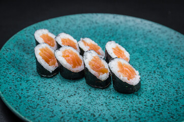 Sushi, traditional Japanese cuisine. Delicious hossomaki on the decorated plate, black background.