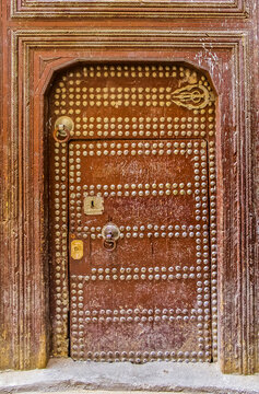Old wooden intricately carved, studded door and door-frame,of a traditional Moroccan house in Fes, Morocco