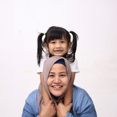 Muslim mother wearing hijab smiling while playing with her baby girl, mom and daughter love each...
