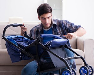 Young father assembling baby pram at home