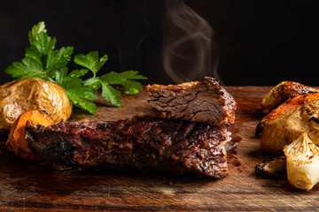 carne asado argentino con papa zanahoria y cebolla sobre madera con fondo oscuro