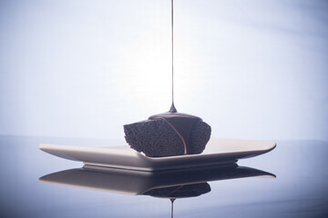 A chocolate cake,serve on a white plate,with flow of chocolate dripping from top,food photography concept