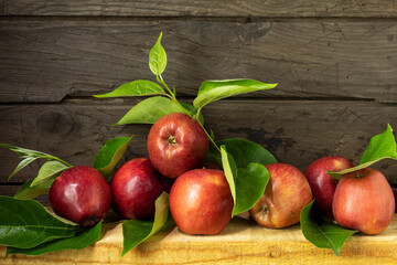 Beautiful background with harvest of red apples in sun rays. Still life with ripe apples on wooden background in rustic style.