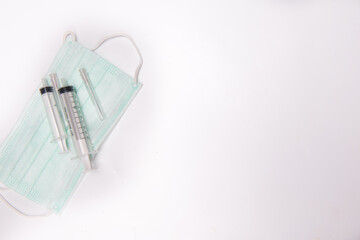 medical syringes and medical face mask,shot from top,spread over white surface