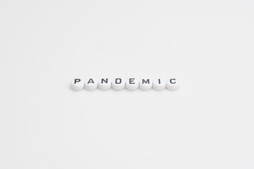 Fototapeta premium The word pandemic in small alphabetical beads, isolated over white