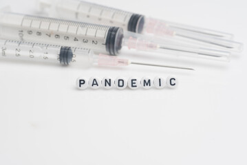 The word pandemic with syringes and medical pills over white background and surface