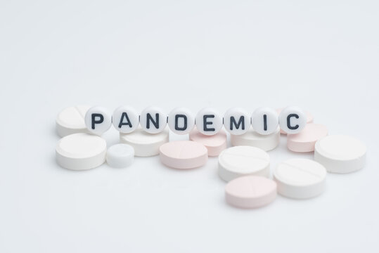 The word pandemic with syringes and medical pills over white background and surface