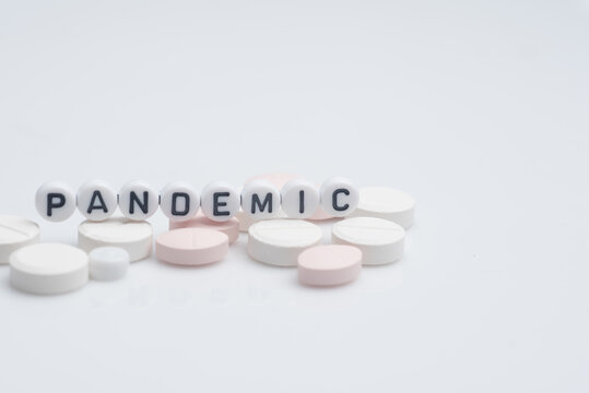 The word pandemic with syringes and medical pills over white background and surface