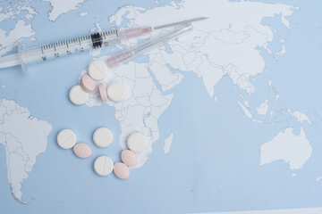 Fototapeta na wymiar Syringes and pills scattered over world map
