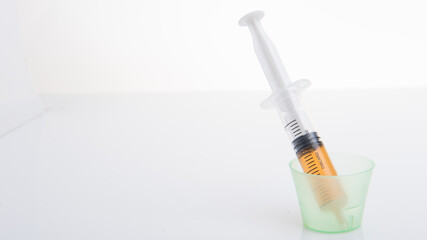 A syringe,filled with orange color liquid isolated over white background,eye level angle