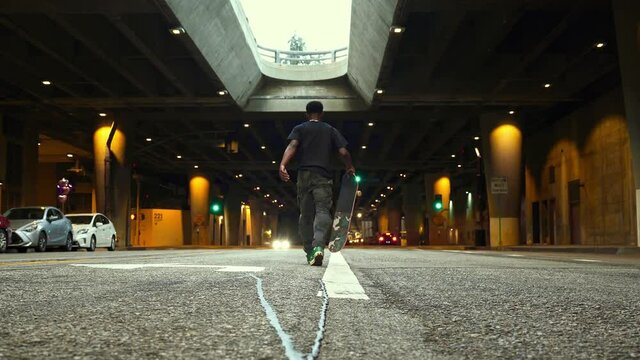 Young athletic african american black male skateboarder doing trick jump in urban garage in Los Angeles. Healthy active lifestyle, adventure, youth, hipster millennial in LA.