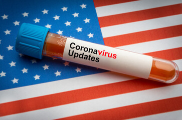 CORONAVIRUS COVID-19 UPDATE text and blood sample vacuum tube on America flags background. Covid-19...
