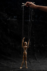 Puppet in the hands of puppeteer walks on isolated, background. The concept of manipulation. Copy...