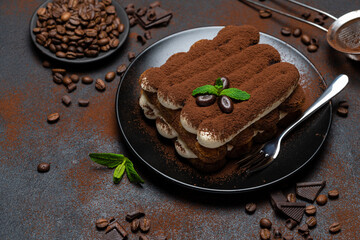 Classic tiramisu dessert on ceramic plate on concrete background