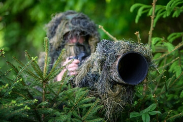 Wildlife photographer in the summer ghillie camouflage suit