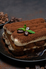 Classic tiramisu dessert on ceramic plate on concrete background