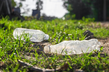 Garbage from plastic bottle that are thrown away on the green grass field in park which is a...