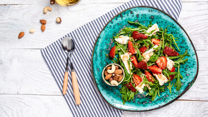 strawberry salad with arugula, brie cheese, camembert. Delicious breakfast or snack on a light background, top view