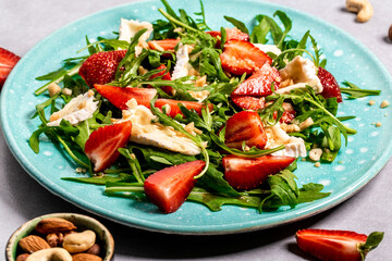 Fresh salad with arugula, strawberries and cheese brie, camembert. Healthy organic diet food concept. Food recipe background. Close up