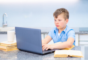 A boy does homework on a computer during distance learning during a coronovirus lockdown