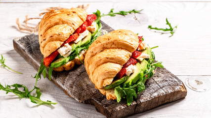 Breakfast of Fresh croissant with arugula, strawberries and cheese brie, camembert. Healthy organic diet food concept. Food recipe background