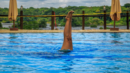 Young girl performs yoga asana underwater.