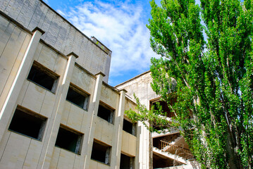 Abandoned building surrounded  by green trees rowing in the centre in Pripyat, a ghost town in northern Ukraine, evacuated the day after the Chernobyl disaster on April 26, 1986