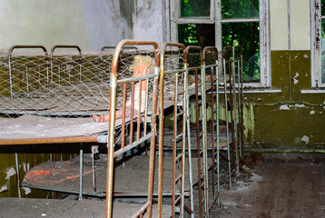 Fototapeta na wymiar Beds in the abandoned kindergarten Pripyat, a ghost town in northern Ukraine, evacuated the day after the Chernobyl disaster on April 26, 1986