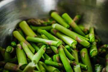 Fresh chopped green asparagus lies in a shiny bowl