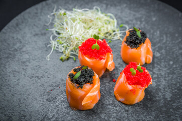 Sushi, traditional Japanese cuisine. Delicious sushi jow com caviar de capellin on decorated plate, black background.