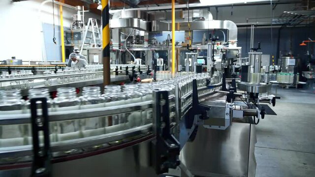 Row of glass bottles on conveyor belt in beverage factory. Robotic production line. packaging warehouse facility. 